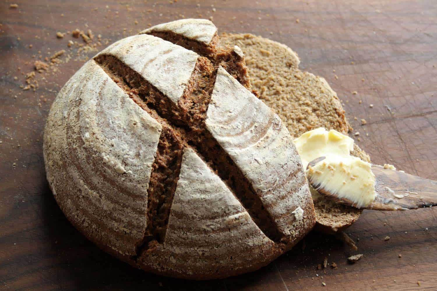 Handmade rye bread with butter on a wooden background