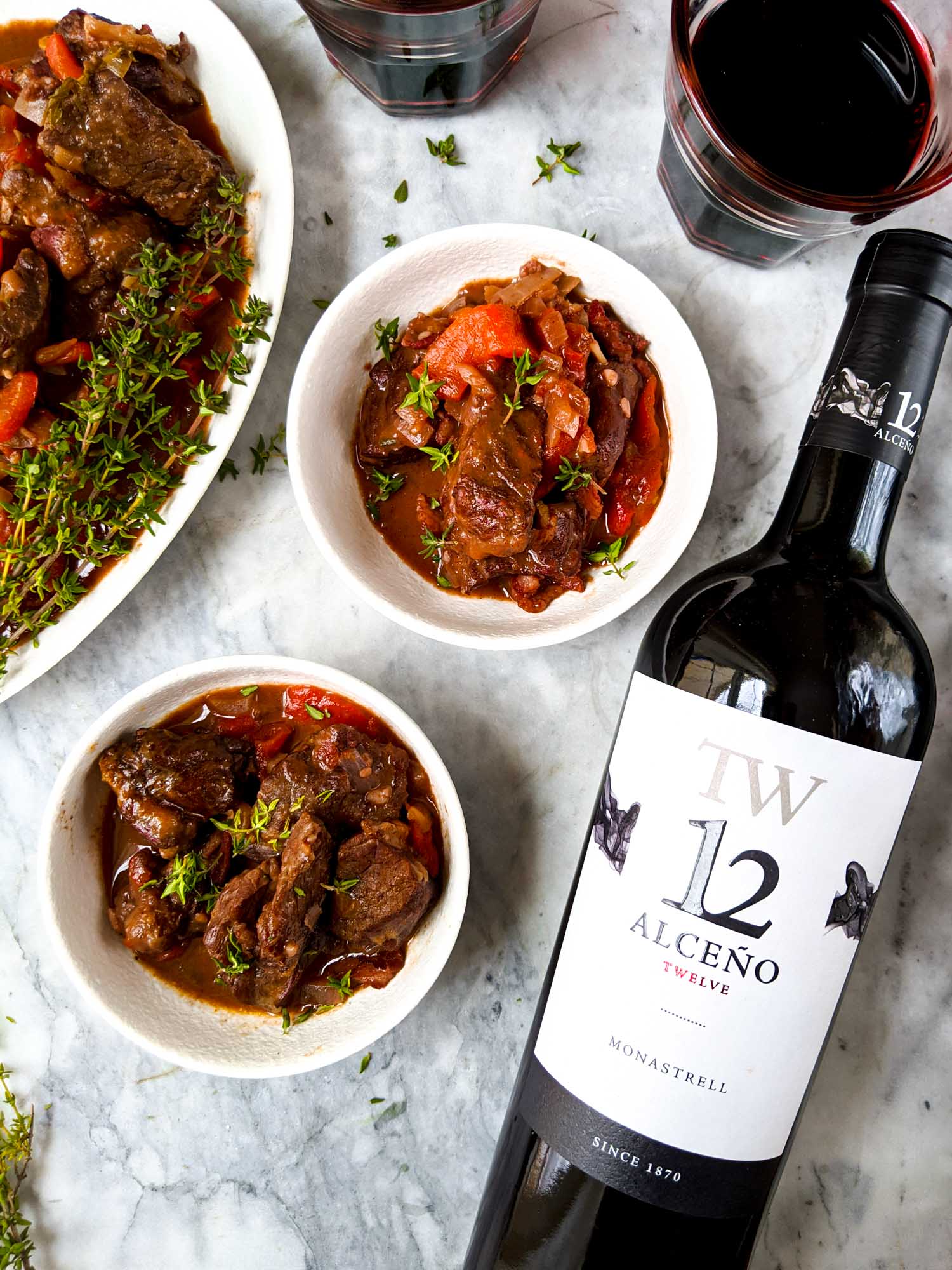 Spanish wine bottle and wine in glasses alongside a Spanish stew.