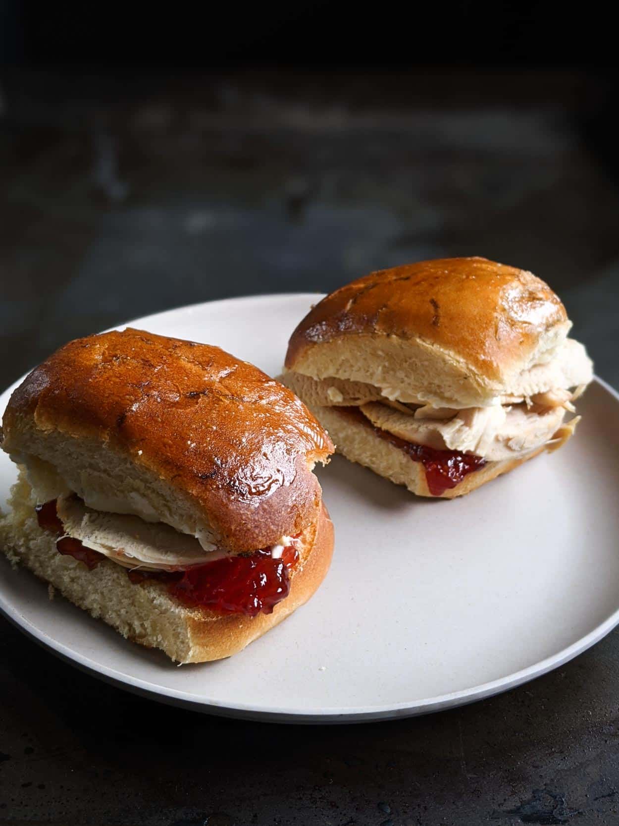 Elena Ruz sandwich, Cuban roasted turkey breast sandwich with strawberry jam, cream cheese on a grey plate and black background.