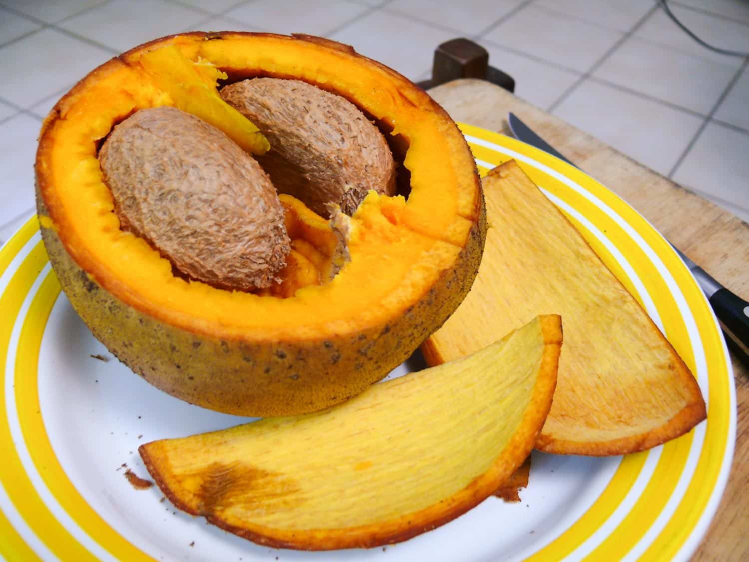Jamaican fruit mammee apple peeled and sliced on a plate to show its interior.