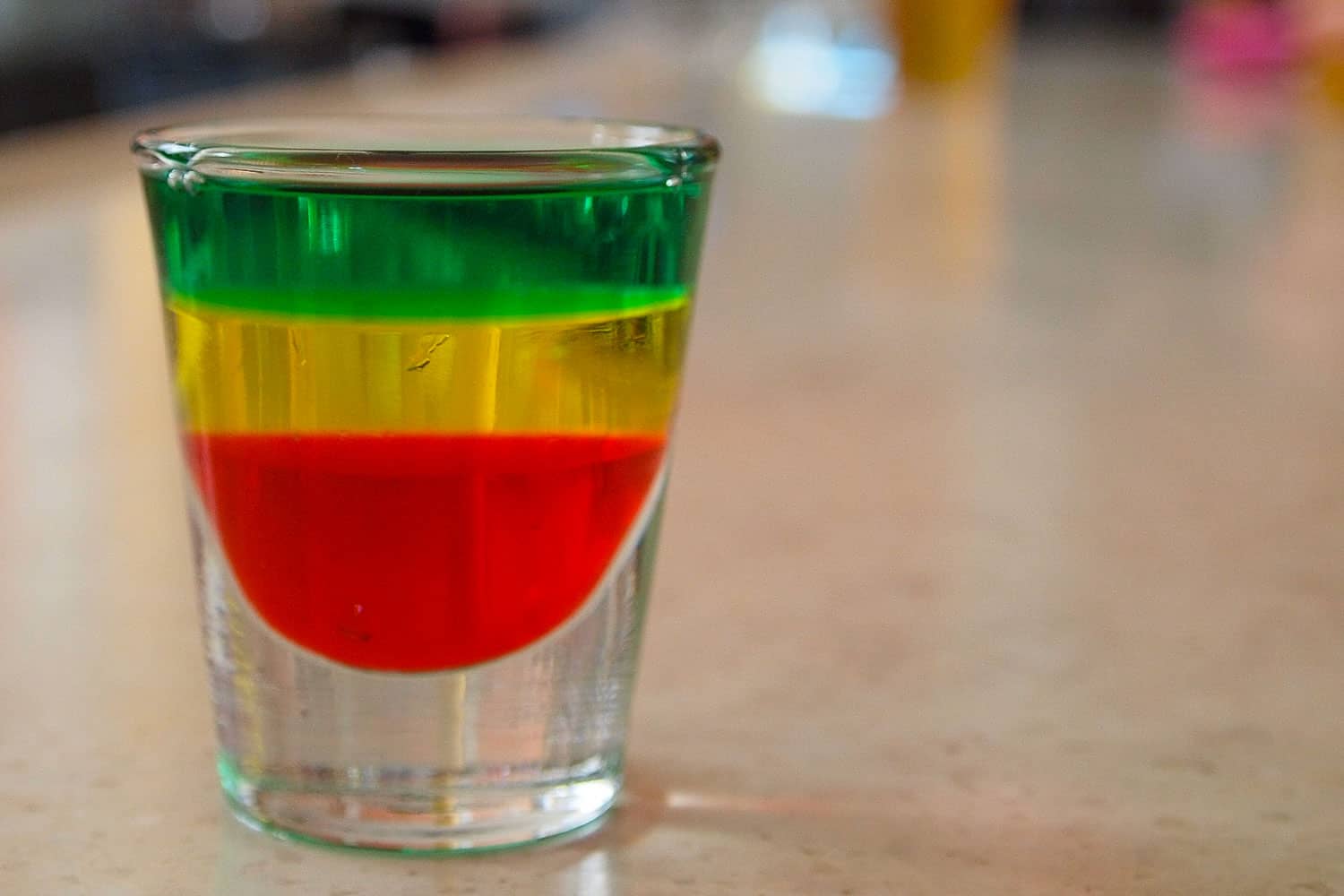 Jamaican cocktail called the Bob Marley shot, which is red, yellow and green on a bar.