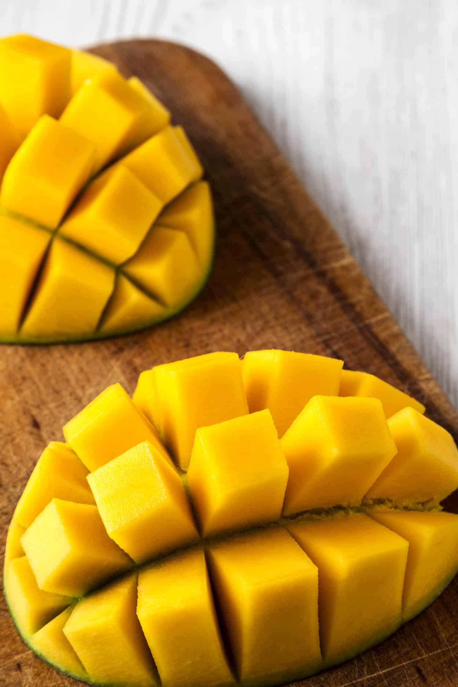 Jamaican mango fruit cut up and ready to eat, rustic wooden board on a white wooden table