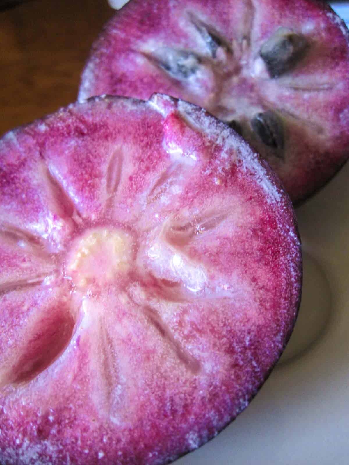 Jamaica fruit called star apple cut in half exposing star like purple flesh.