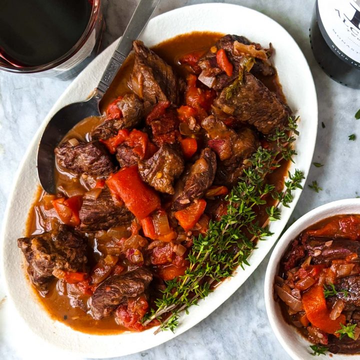 Spanish beef stew on a white plate with a spoon.