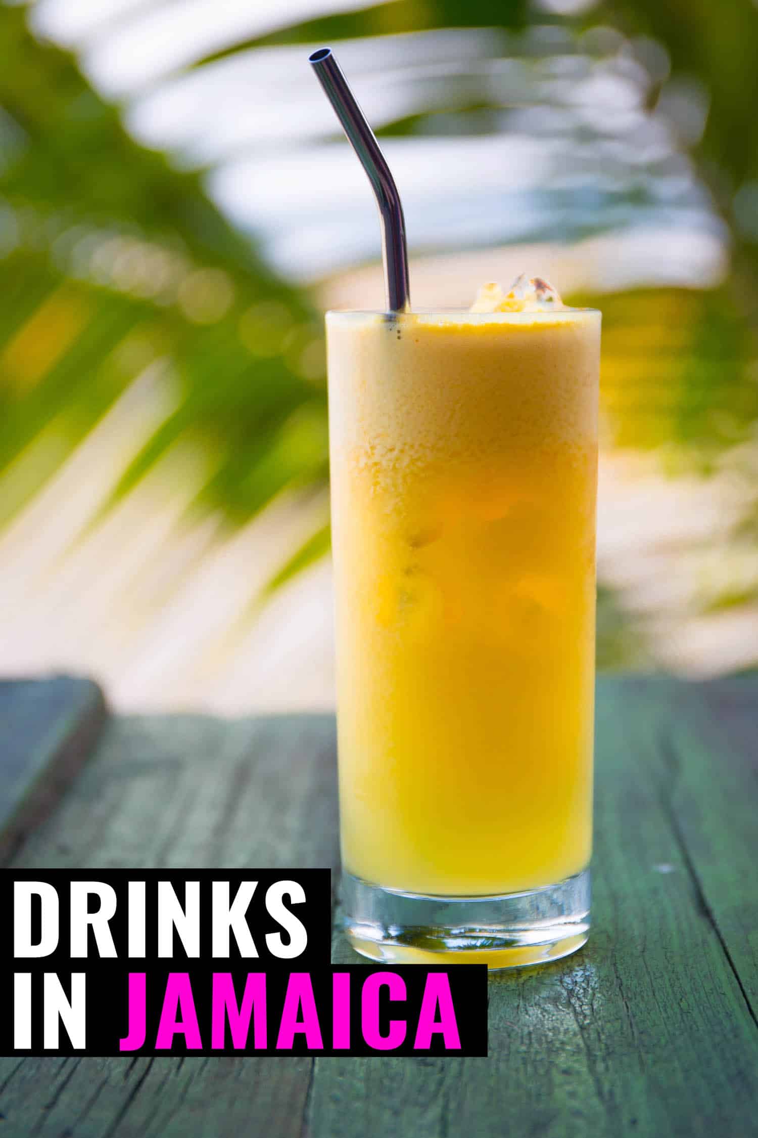 Tropical Jamaican drink on a table with palm trees in the back