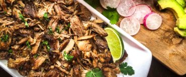 Instant pot pork carnitas on a tray with sauce, radishes and lime