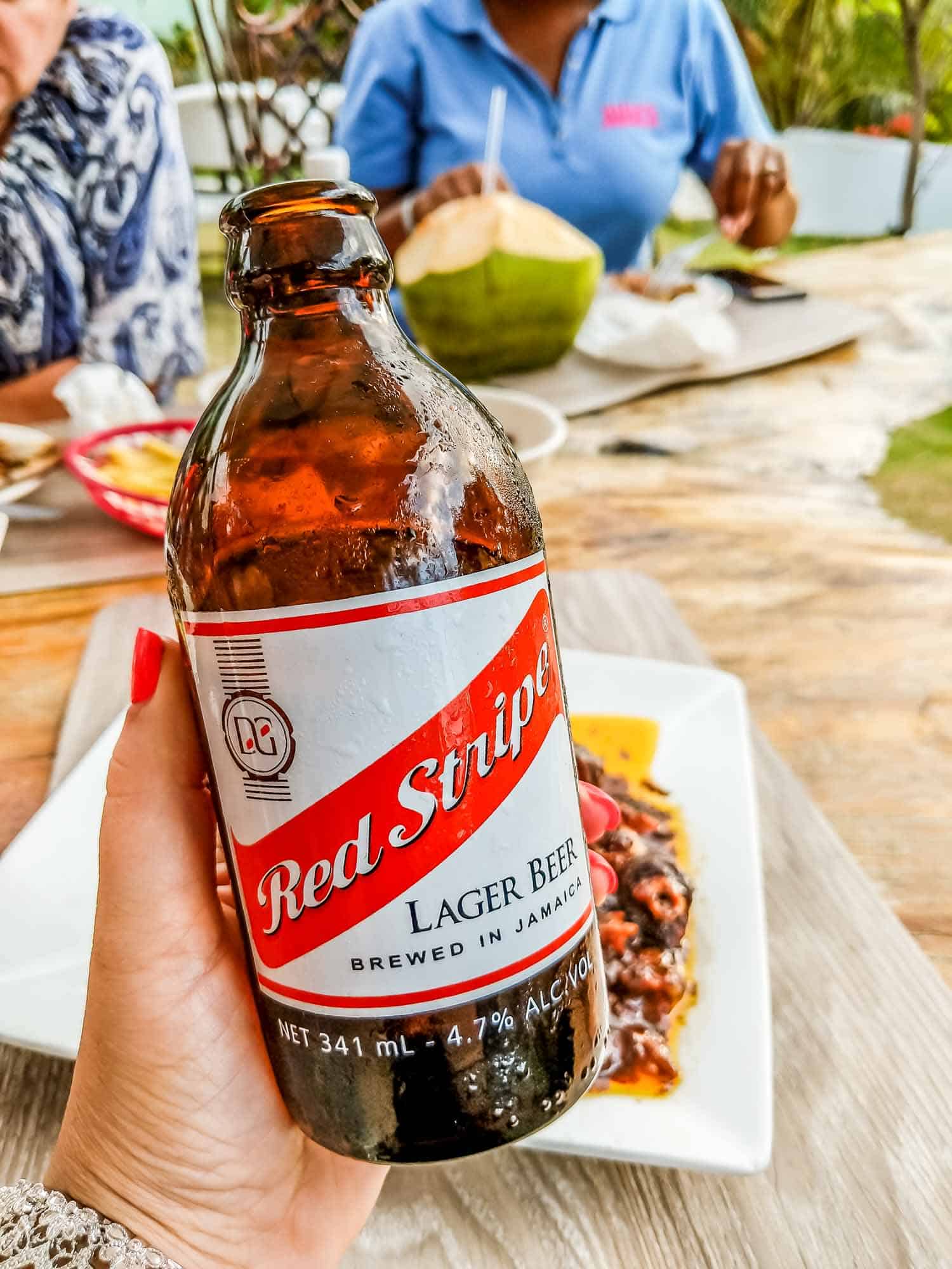 Red Stripe beer, popular drinks in Jamaica in a woman's hand