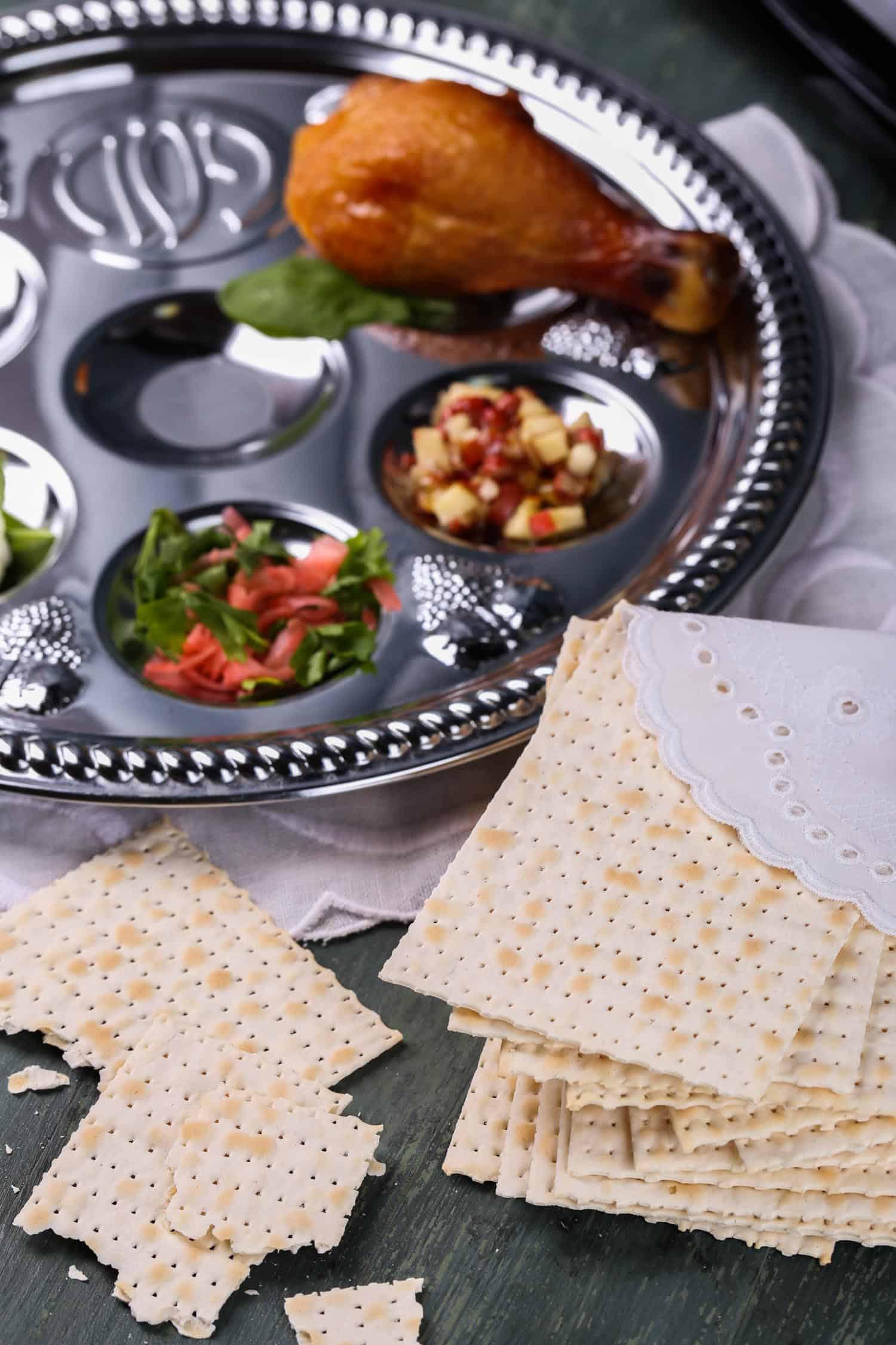 Passover seder plate with symbolic passover food and matzo cracker on the side.