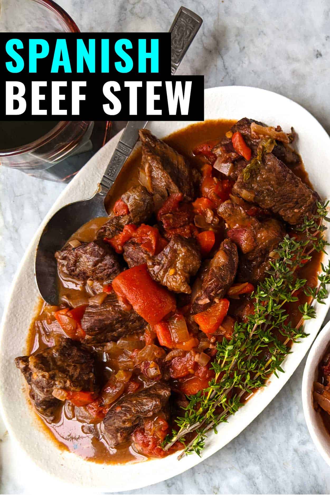 Spanish beef stew on a white plate with a spoon.