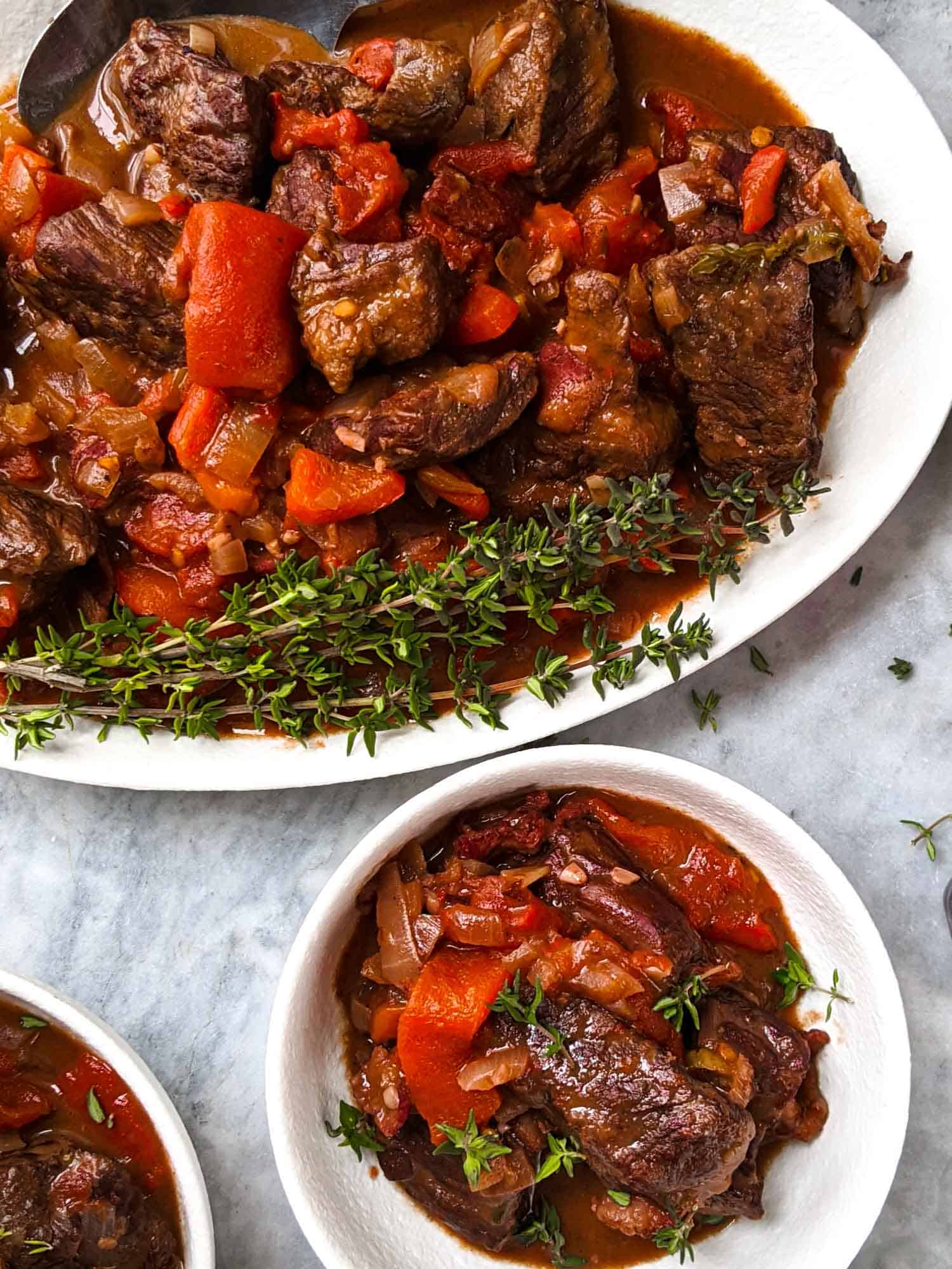 Red wine Spanish stew on white plates in a marble background