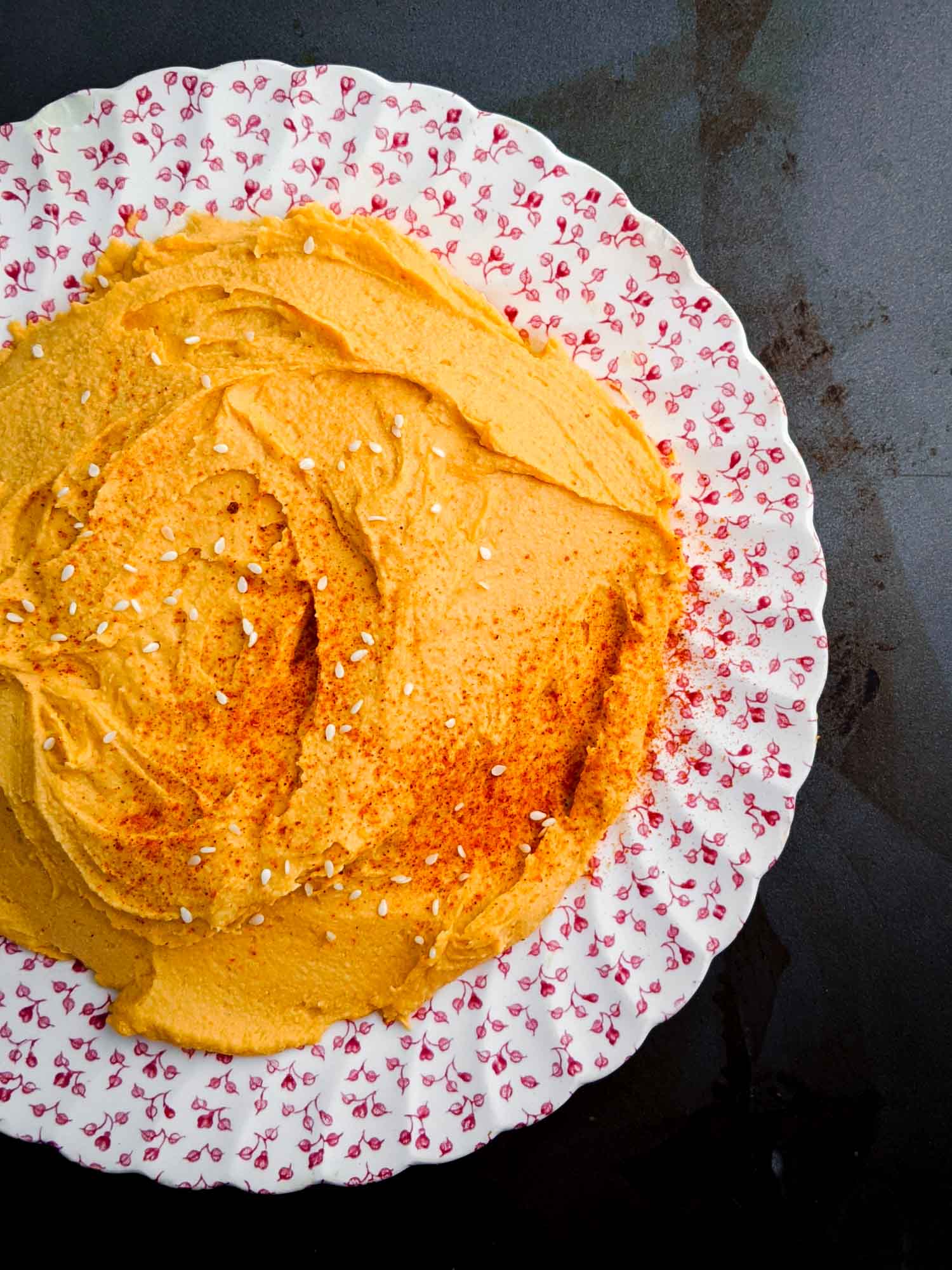 Sriracha hummus on vintage plate and dark background.