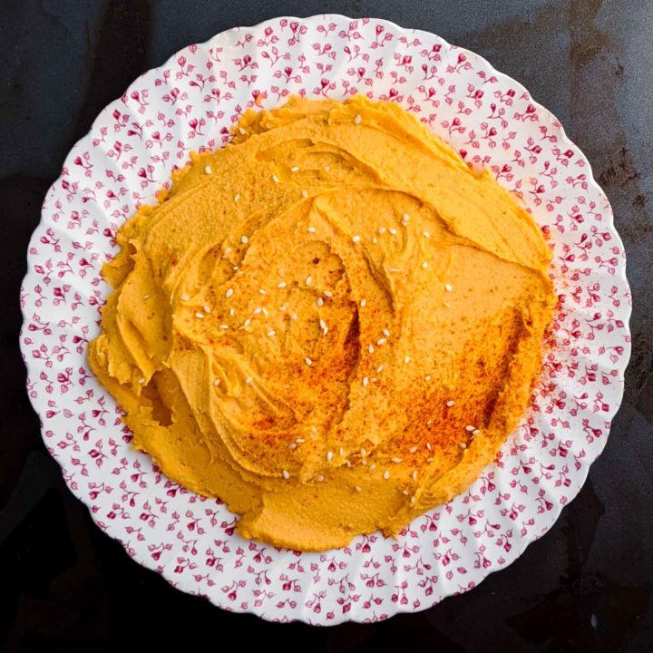 Sriracha hummus on vintage plate and dark background.