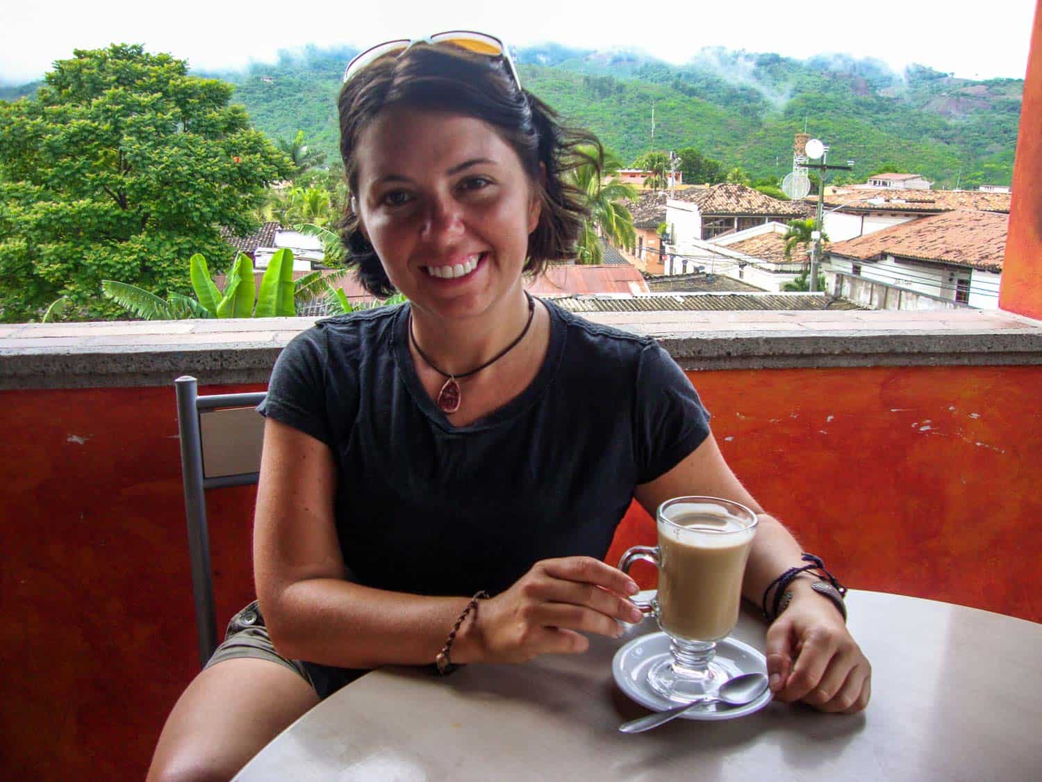 Ayngelina at a table with coffee, views of Copan Honduras in the background