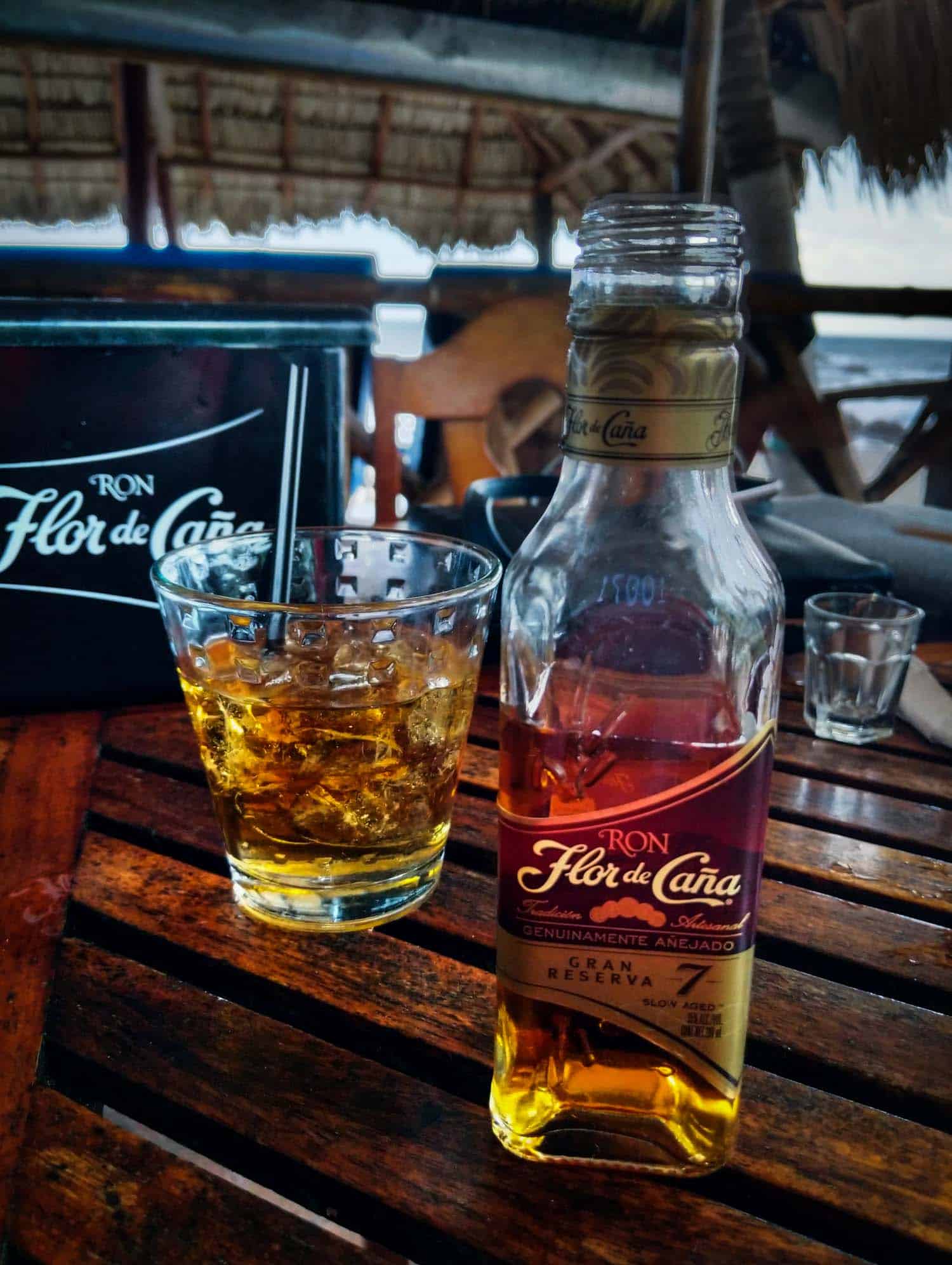 Bottle of Flor de Cana rum on a table with a glass behind it