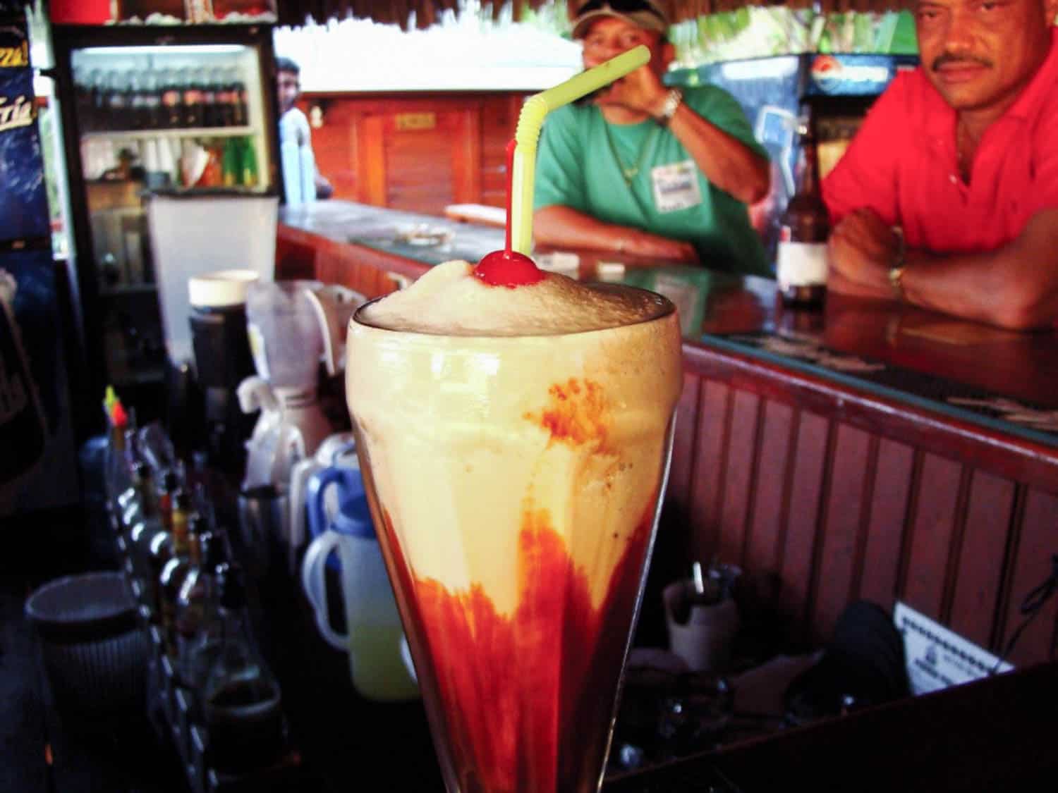 Monkey lala cocktail popular Honduran drink in Roatan island, on a table at a bar with locals in the background