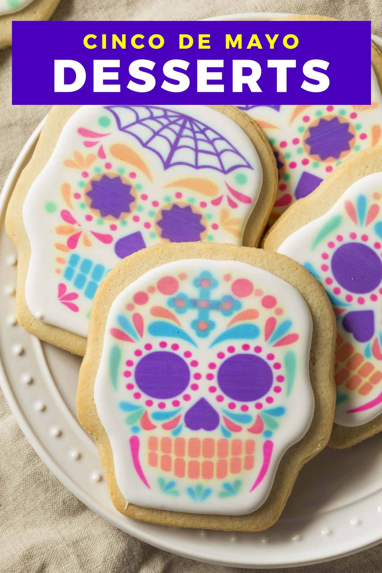 Sugar skulls, a popular Mexican cookie and Cinco de Mayo dessert, on a white plate on white tablecloth