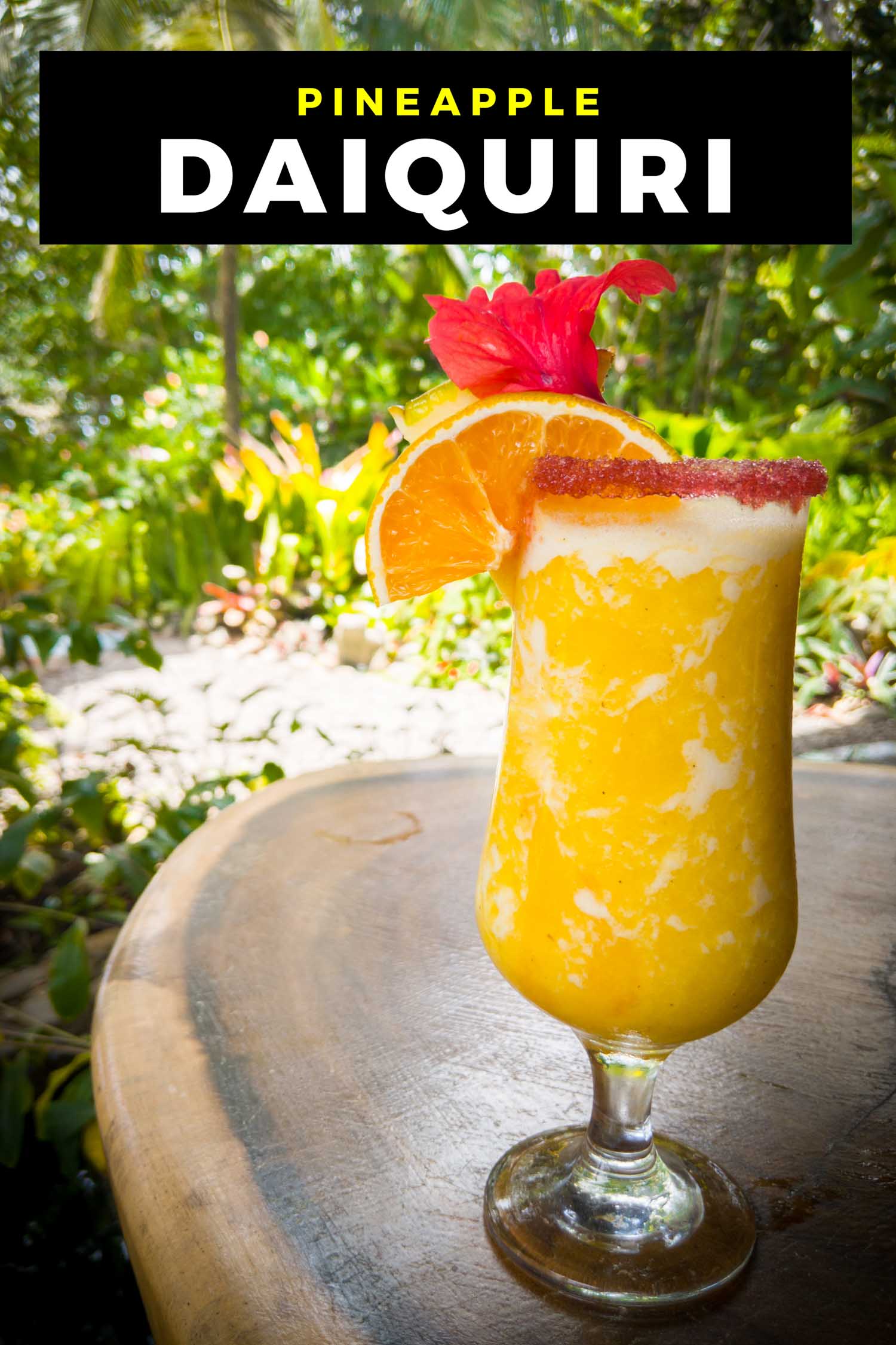 Frozen pineapple cocktail on a table, garnished with a hibiscus flower and an orange