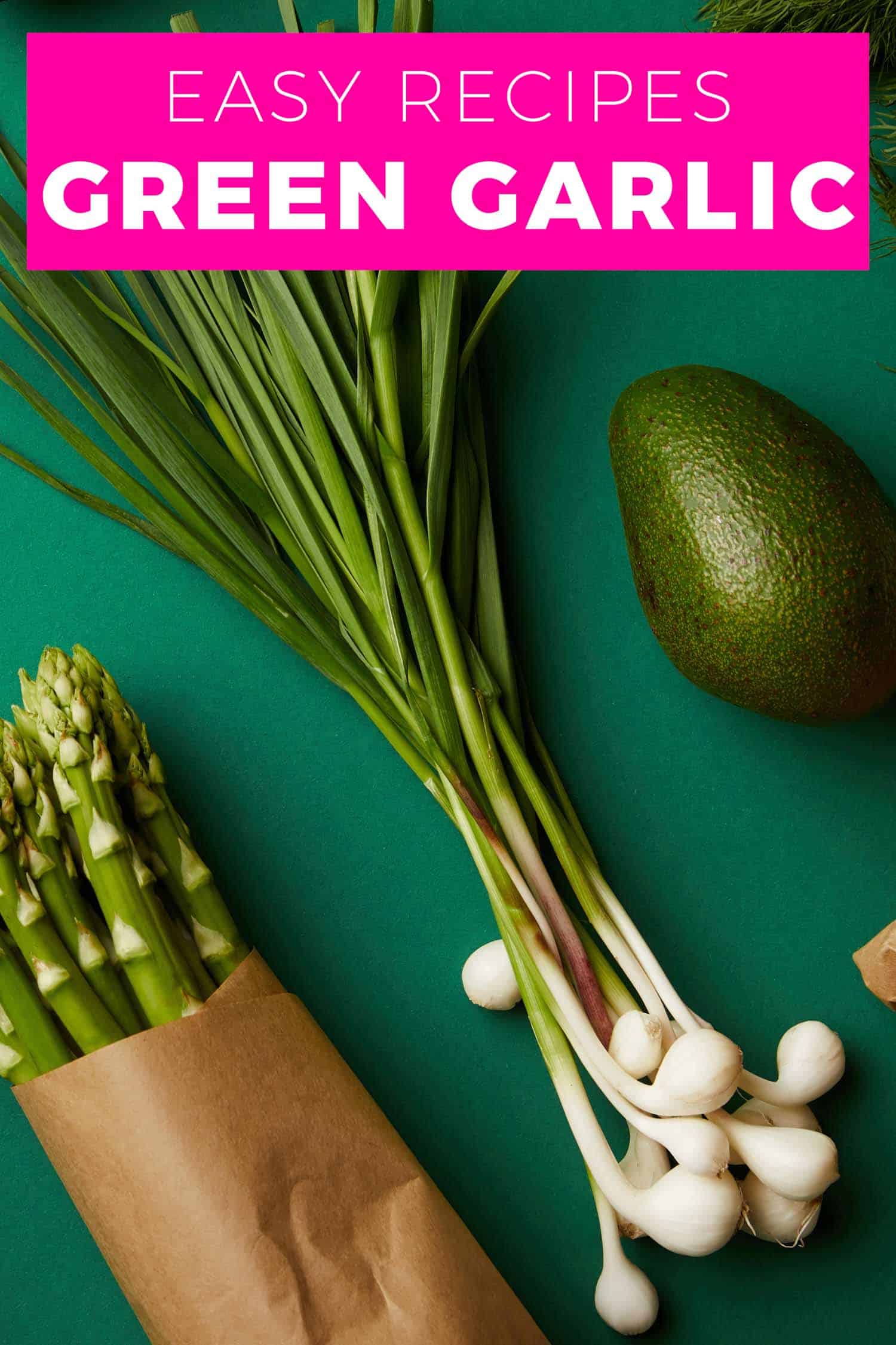 Green garlic on a green background alongside asparagus and avocado