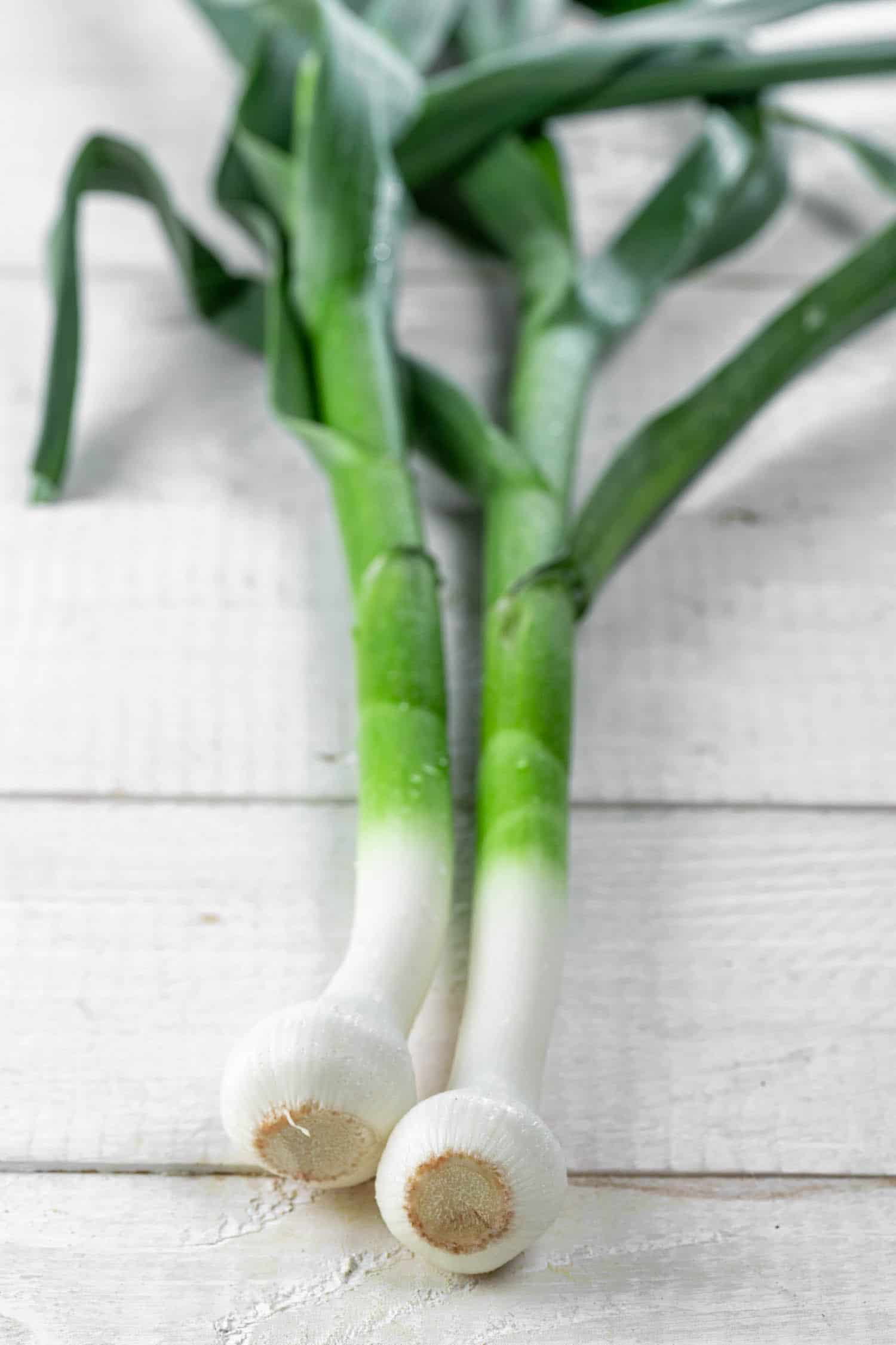 two green garlic on a white table