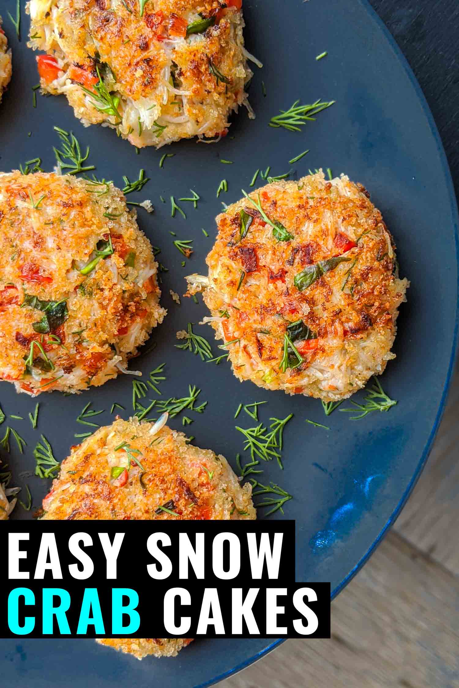 Snow crab cakes on a blue plate with dill garnish