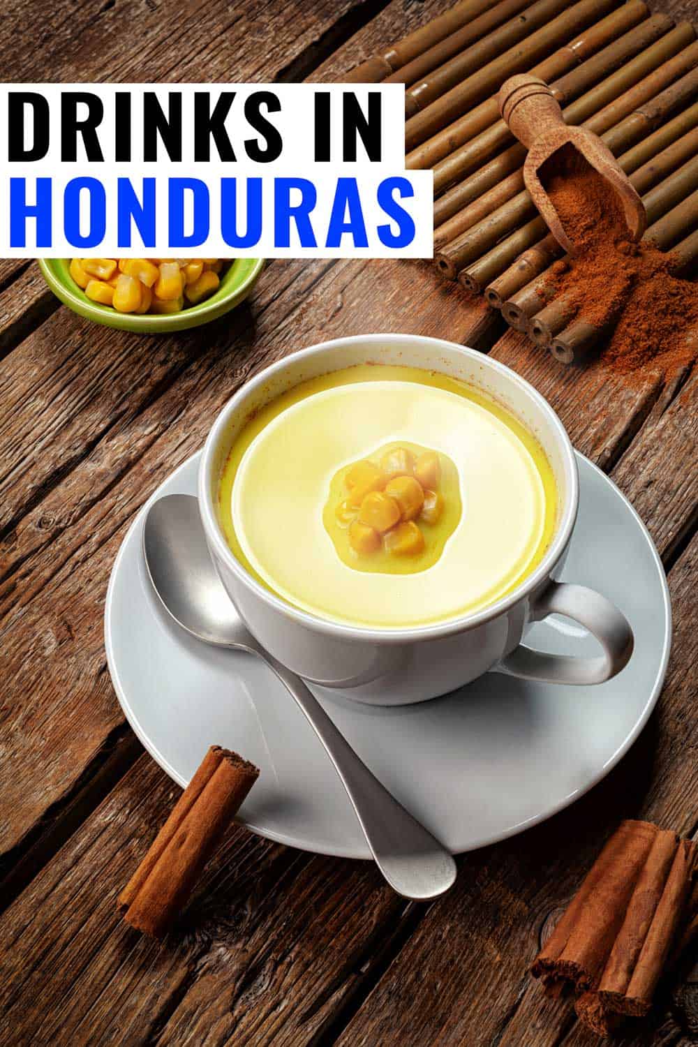 Atol de elote, one of the most common Honduran drinks, on a table with corn and cinnamon garnishes.