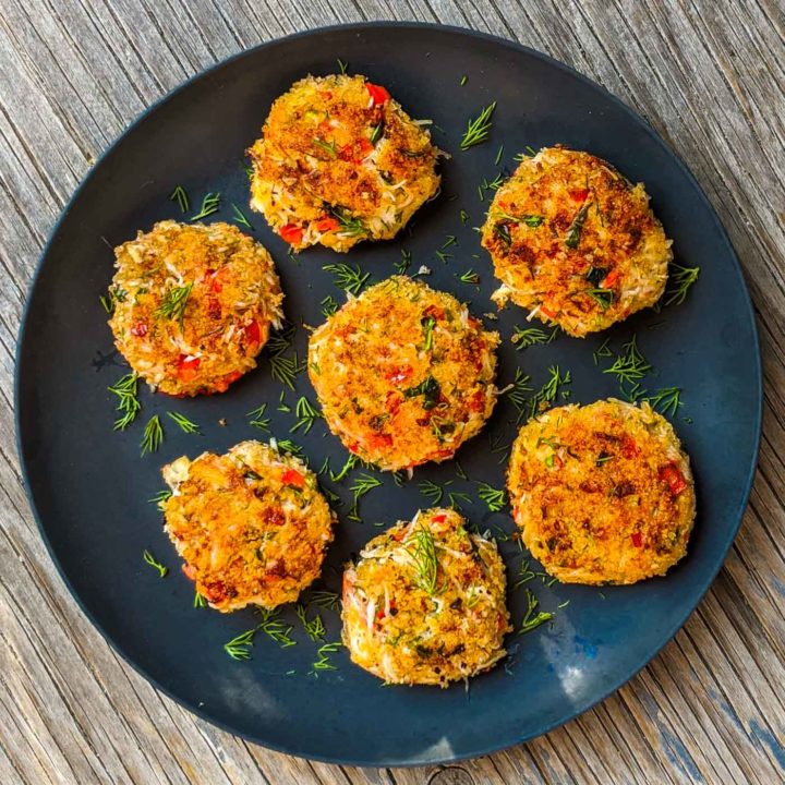 Seven snow crab cakes on a blue plate on a rustic background.
