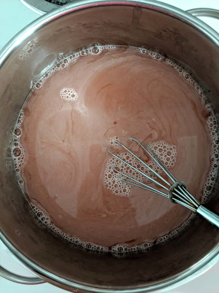 Rhubarb soda called rhabarberschorle in a pot cooking down with whisk