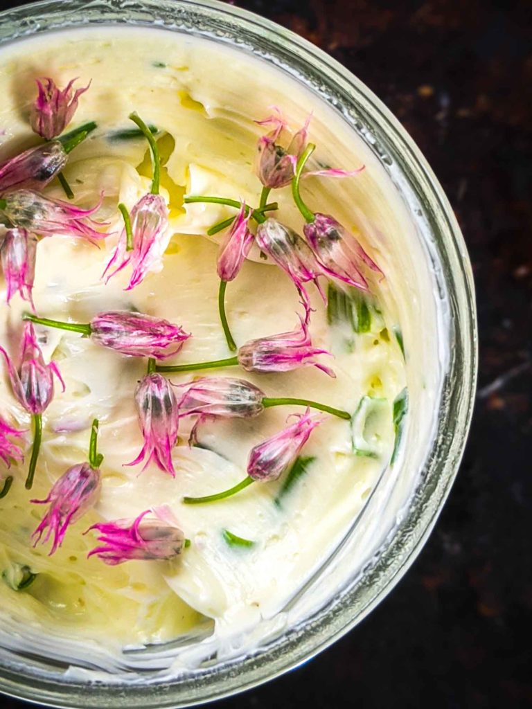 close up of chive butter in a mason jar on a dark background