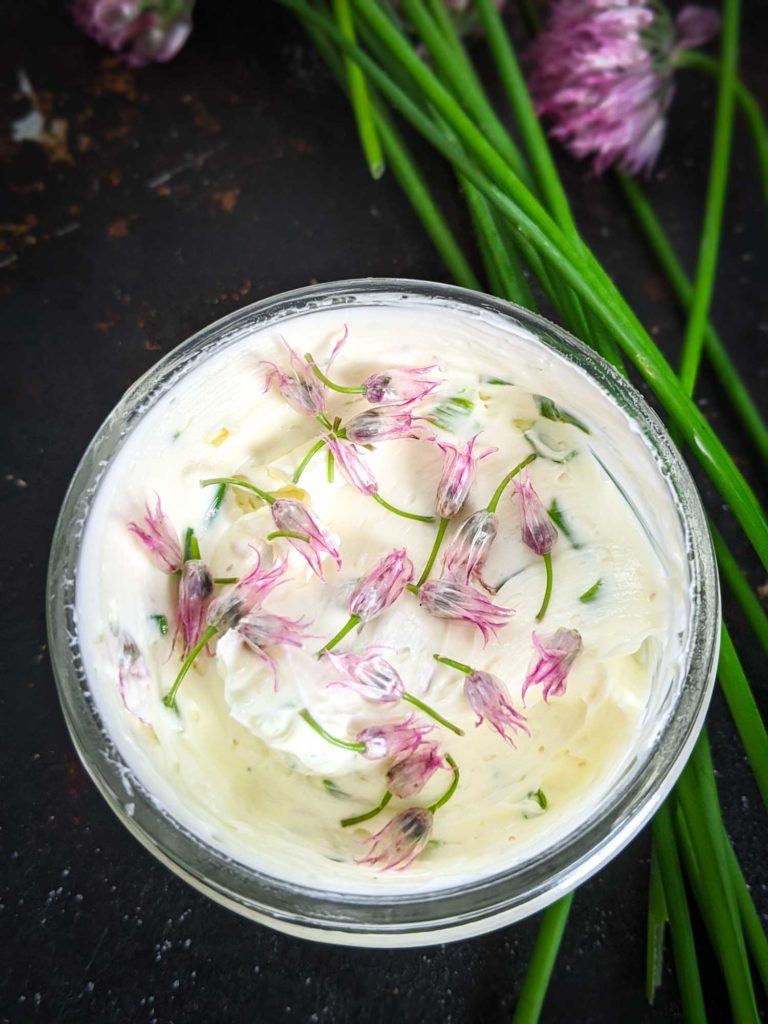 chive butter in a mason jar on a dark background with chives in the corner