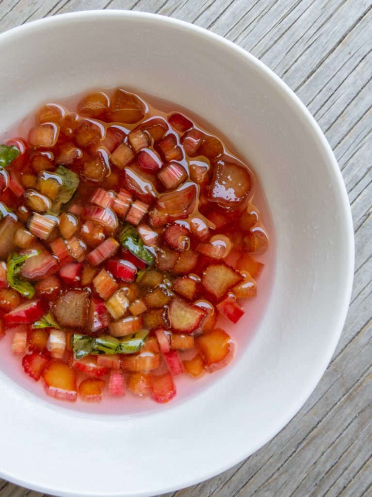 rhubarb macerating in sugar in a white bowl on a wooden background