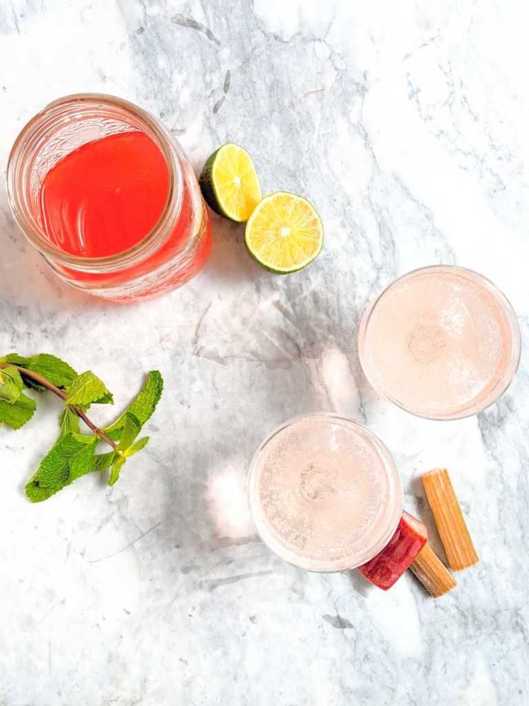 Rhubarb soda called rhabarberschorle with ingredients, facing top down on a marble background