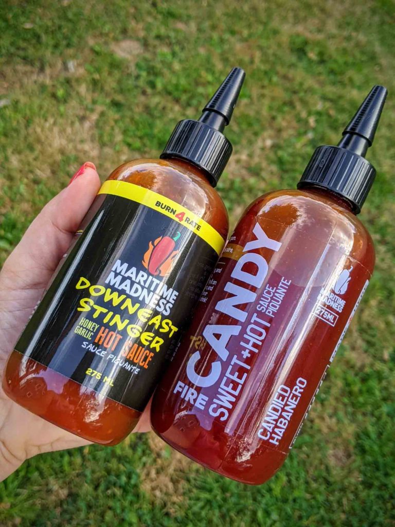 Hand holding two types of hot sauce