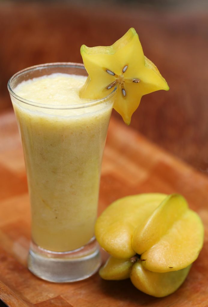 Carambola or starfruit juice in a glass with ripe fruit