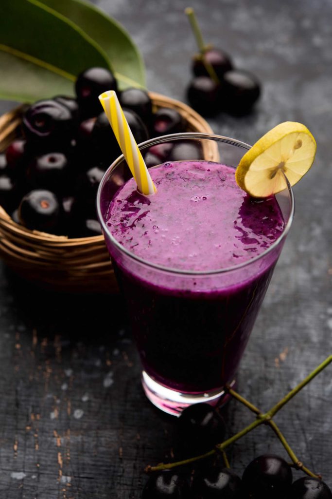 Java plum juice with fruits behind it