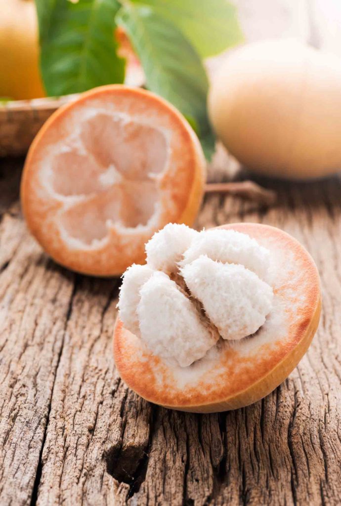 sliced santol fruit on wooden background, the famous fruit of Lop Buri, Thailand and seasonal fruit on june.