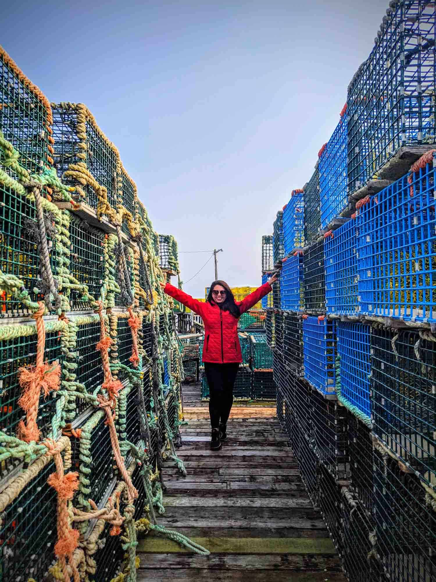 Ayngelina in red coat standing between lobster traps at Tusket Island Tours