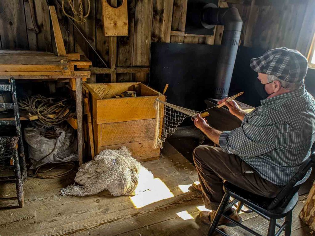 Man sitting at Historic Acadian Village making a fishing net.