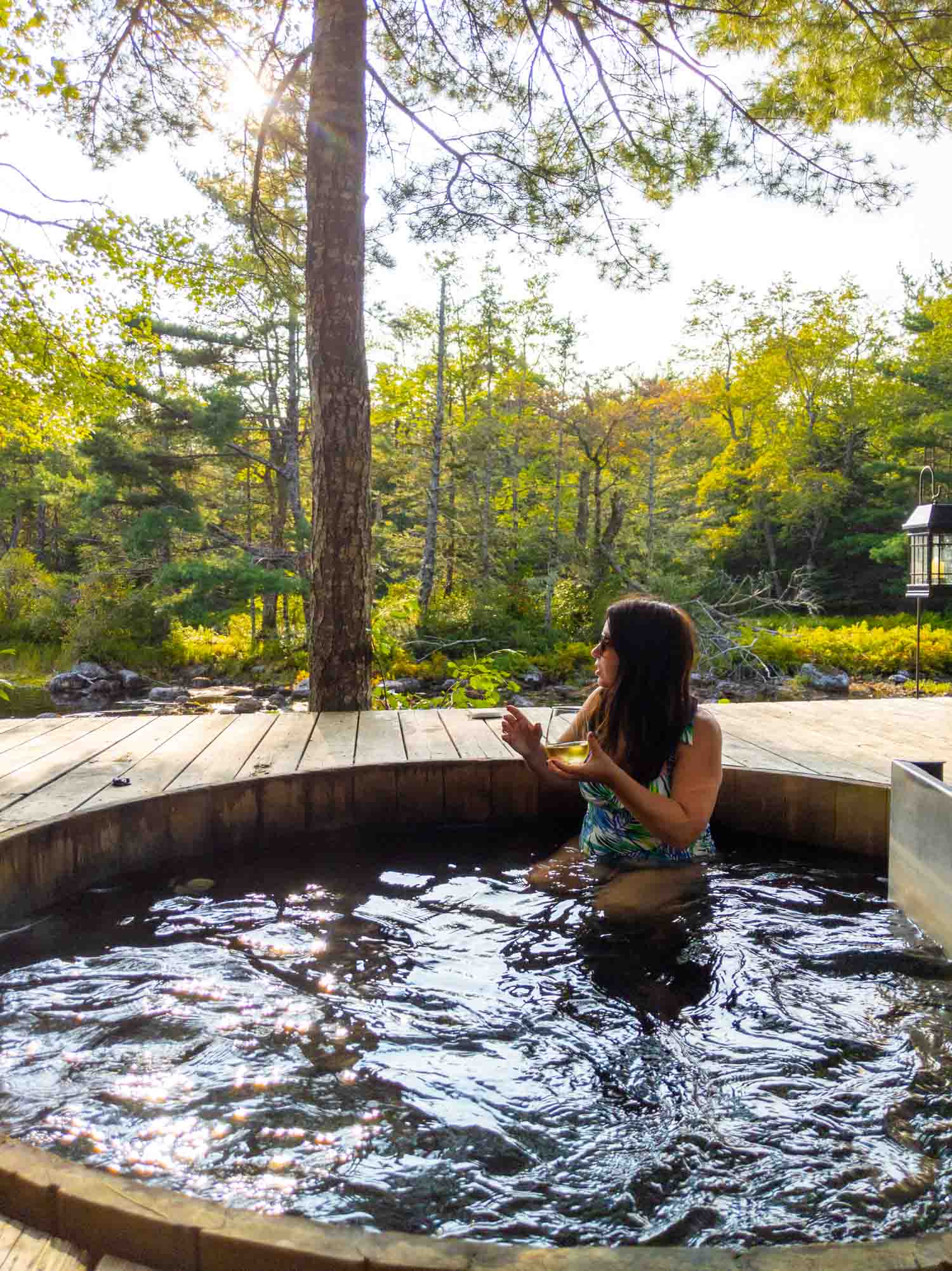 Woman in wood fired hot tub in autumn at Trout Point Lodge