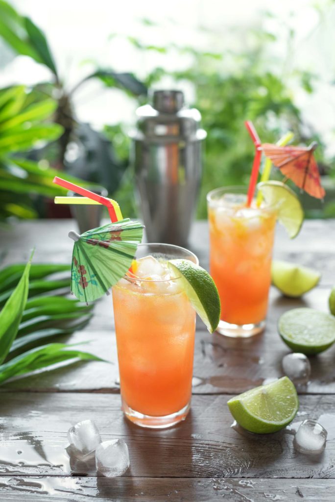 Zombie Cocktail with Rum, garnished with lime. Cold sweet summer fruit red alcohol cocktail, refreshing drink on wooden table, copy space.