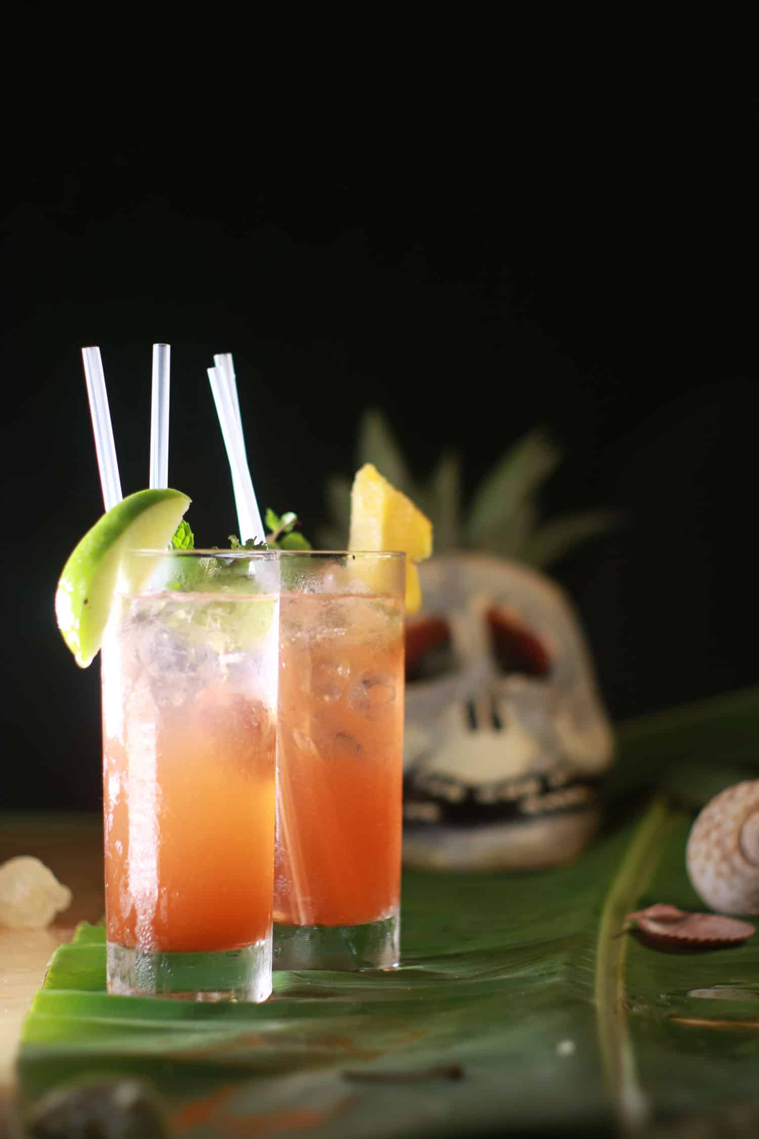 Two zombie cocktails against black background with skull for Halloween drinks.