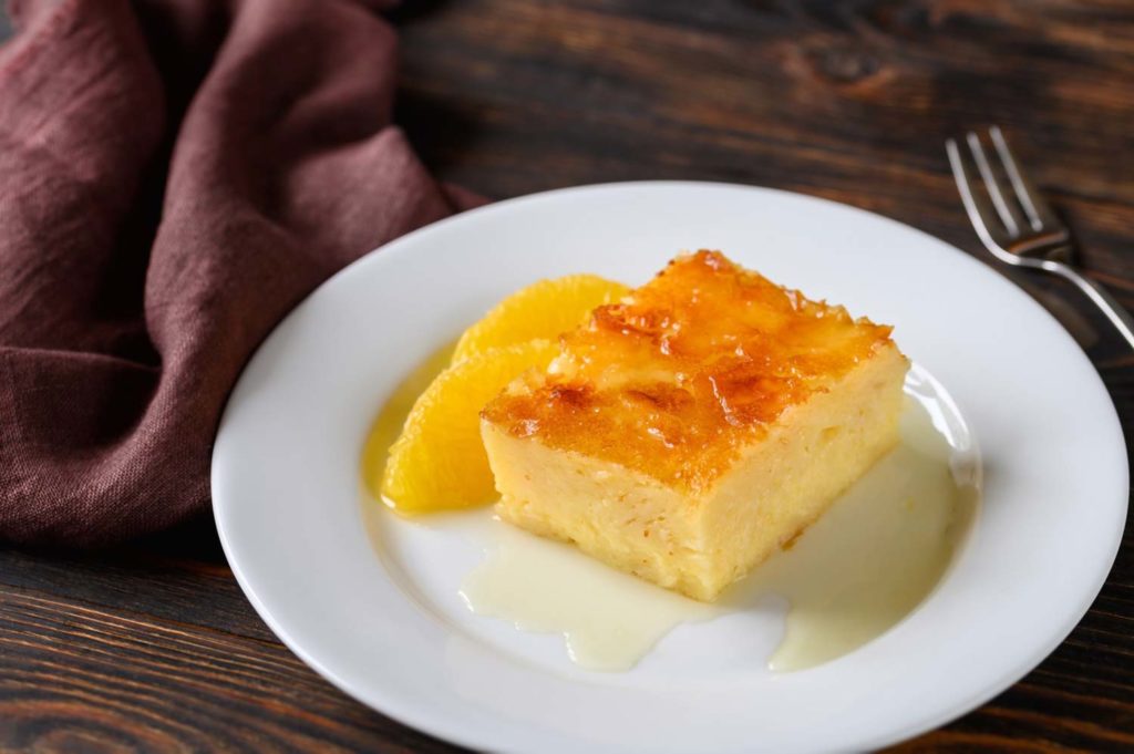 Dessert in Guatemala called borracho which is a sponge cake soaked in rum on a white plate garnished with orange