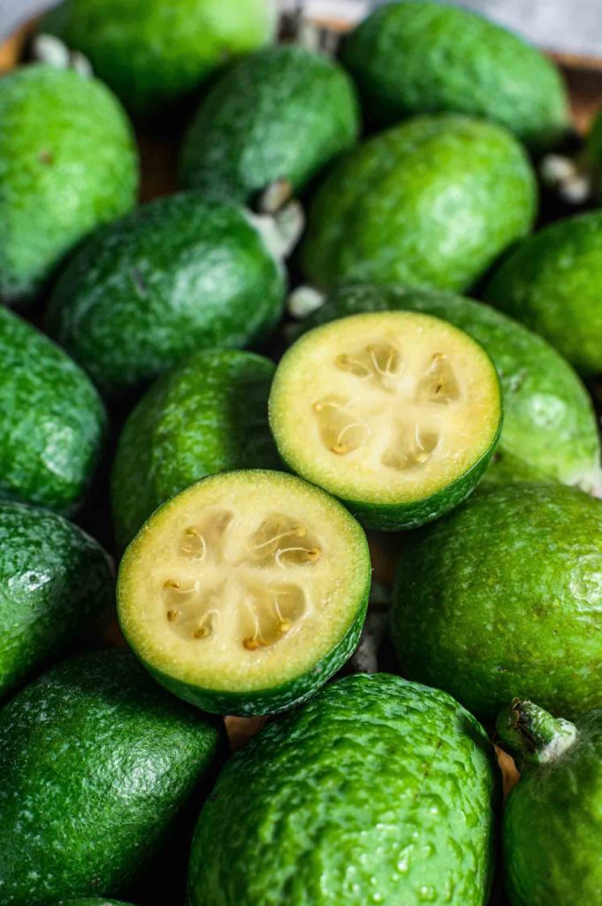 Green feijoa on a wooden board. Gray background. Top view. Close up.