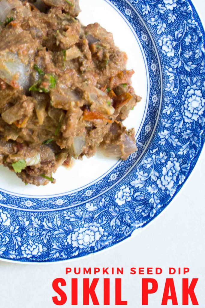 Sikil pak, a Mayan pumpkin seed dip on a blue plate and white background.