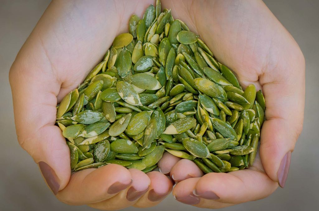 Pepitas or Mexican pumpkin seeds in woman's hand in shape a heart