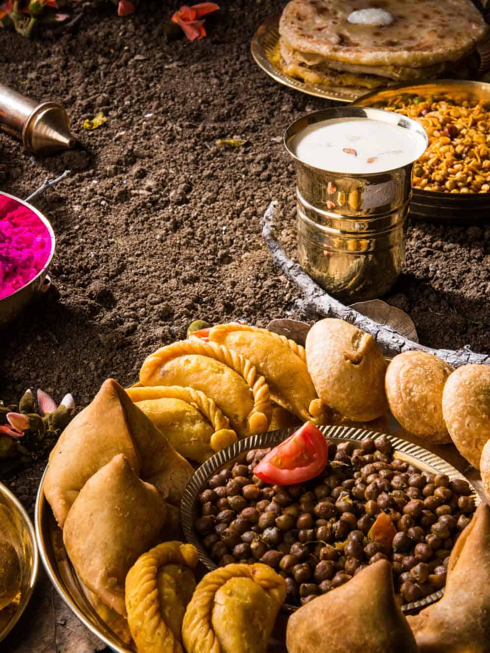 holi festival food with colours, indian festival holi, samosa, kachori, laddu, gujiya, palash flower, thandai, farsan, chana masala, puran poli or roti, indian festival of colours called holi