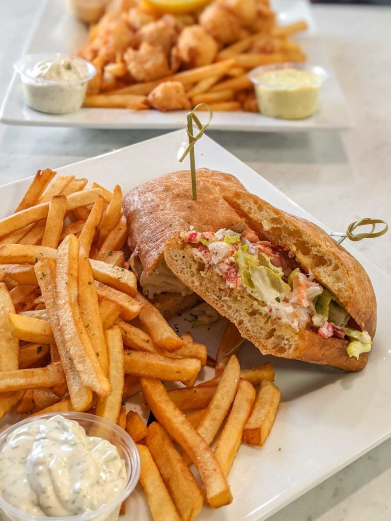 Winners One Stop restaurant in Yarmouth NS lobster roll and fries with scallops and fries in the background.