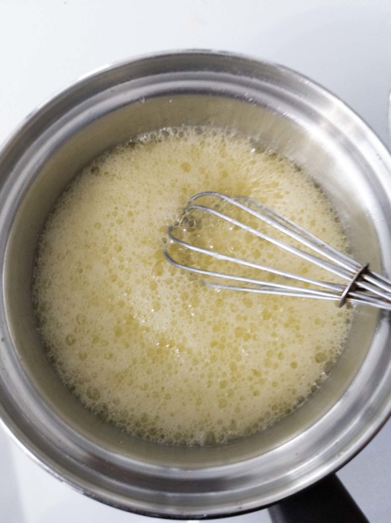 Butter browning in pot with whisk, foaming up.