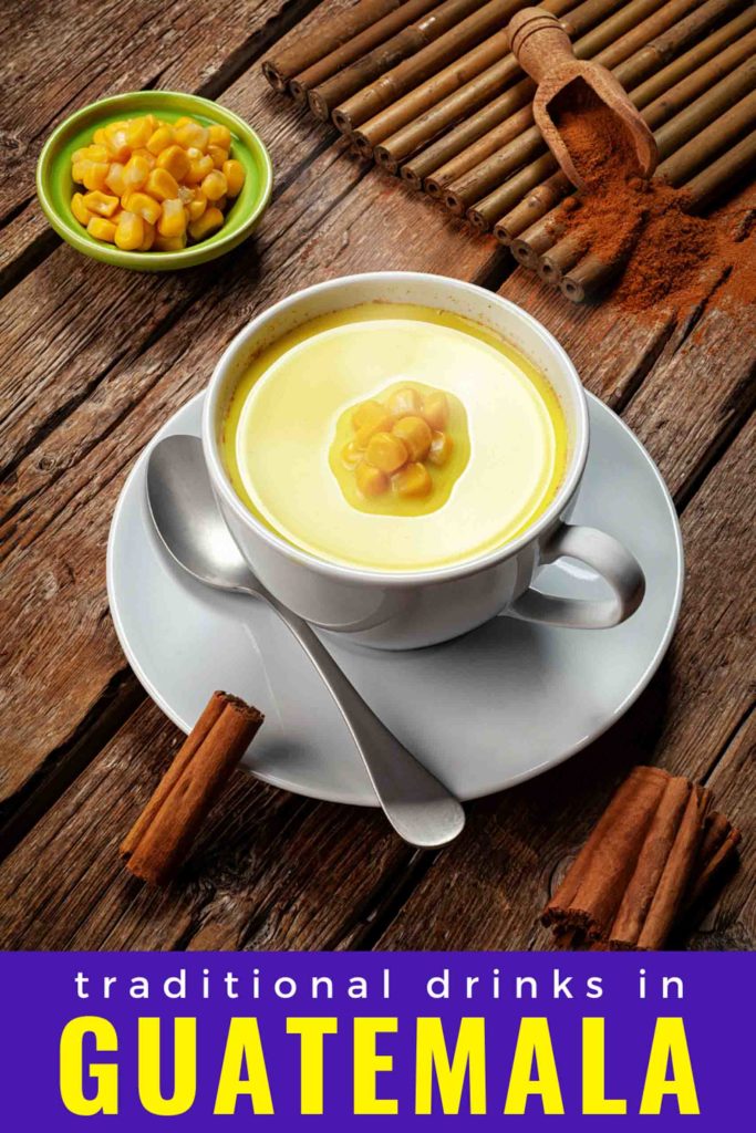 Atole de elote corn drink in a tea cup on a wooden background with cinnamon and corn garnishes