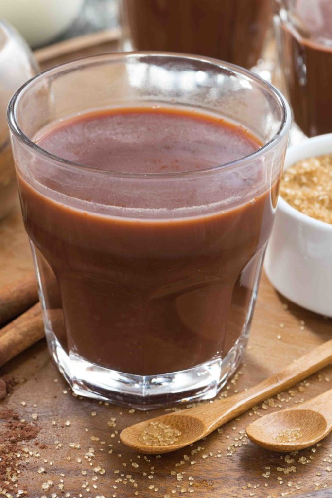 glass of cocoa with spices on a wooden tray, close-up, vertical, top view