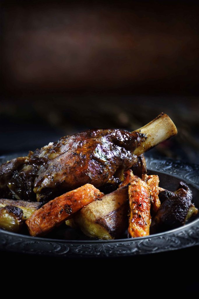 Roasted lamb shank in Iceland with root vegetables of parsnip, carrots and shallots.